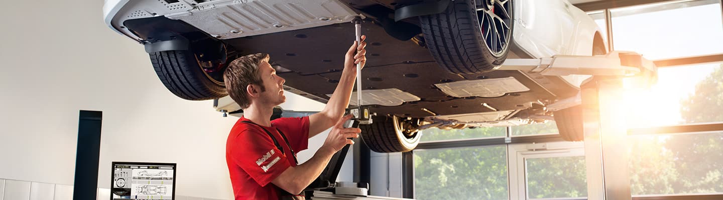 Car repair service under a vehicle, available at Porsche Oklahoma City