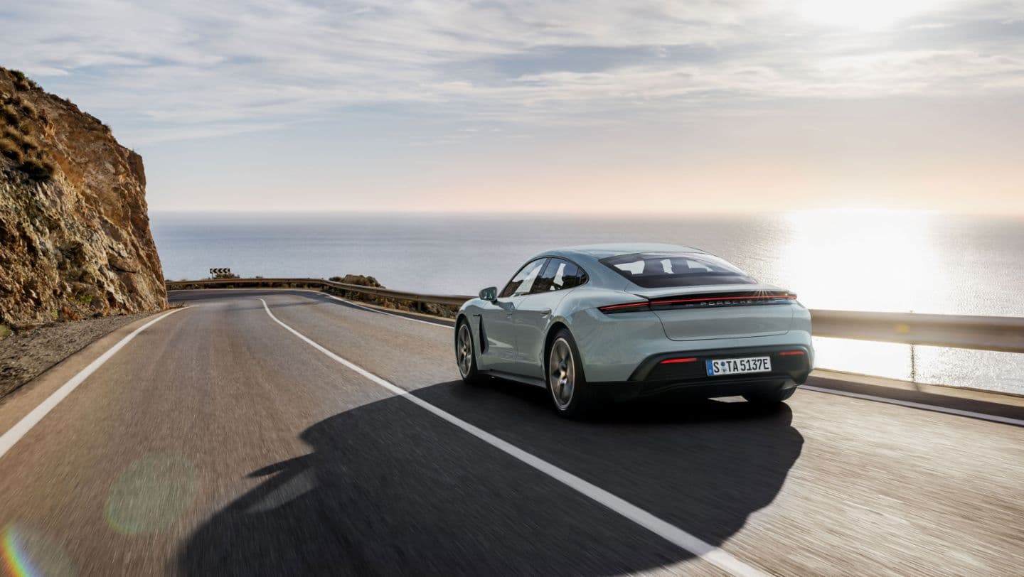 2025 Porsche Taycan Turbo in Shade Green Metallic driving down Pacific Cost Highway.