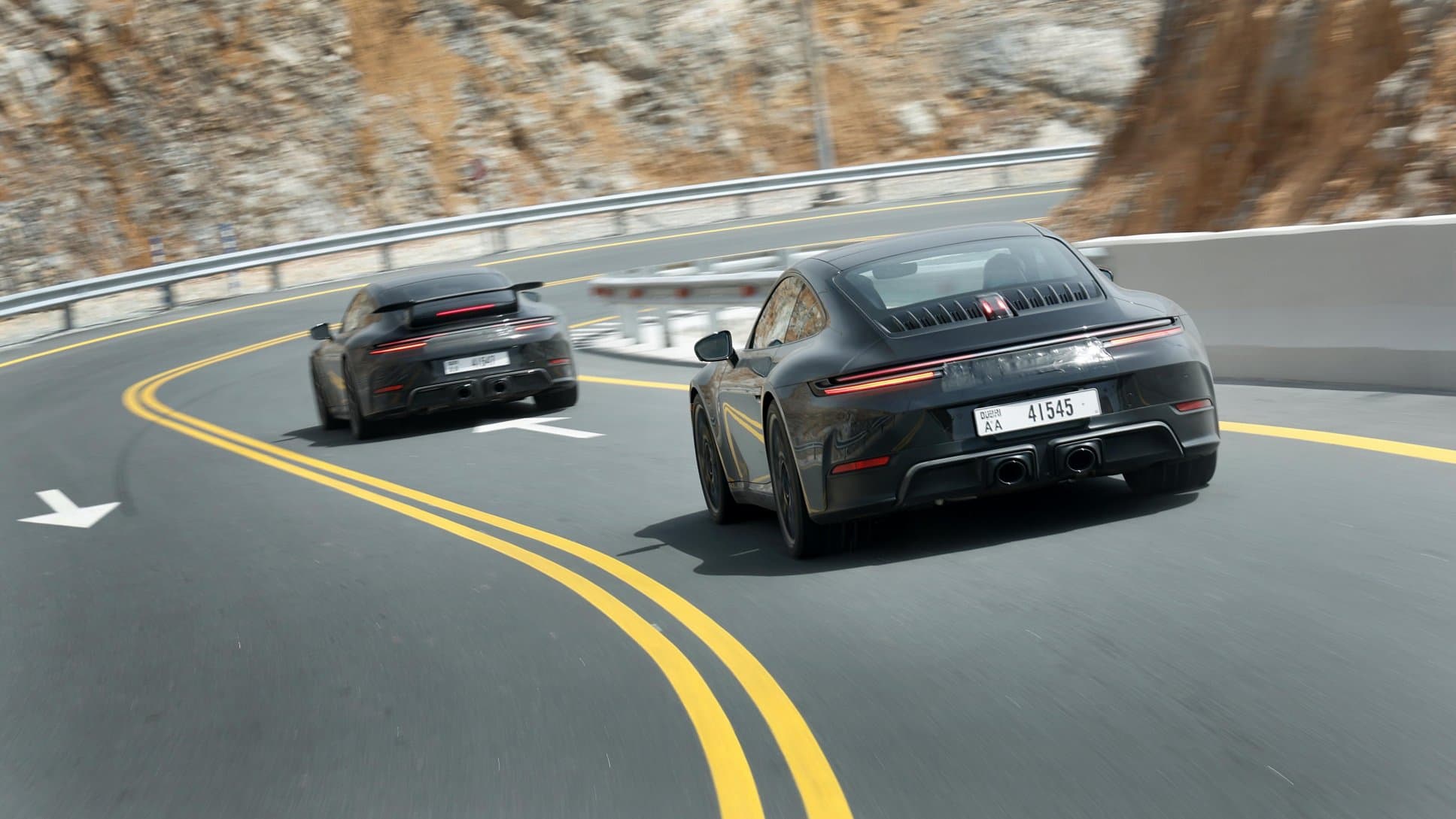 2025 Porsche 911 driving on curvy road through mountains.