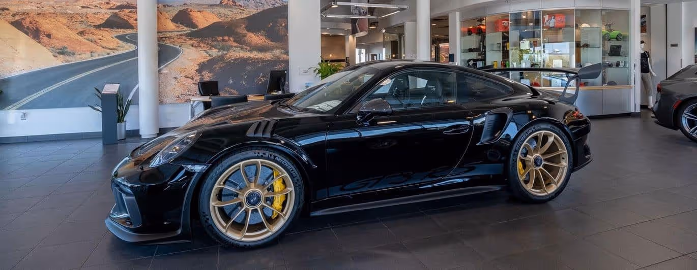 New 2023 911 GT3 RS black exterior, bronze wheels, wing and yellow big break kit parked on Porsche Oklahoma City show floor.